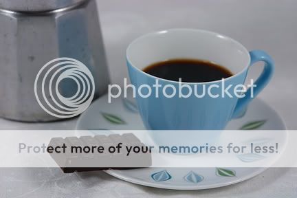 photo of espresso maker, pottery cup and chocolate bar